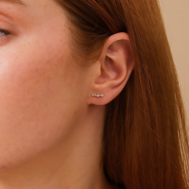 Model wears petite solid 14k gold curved bar stud with multiple diamonds