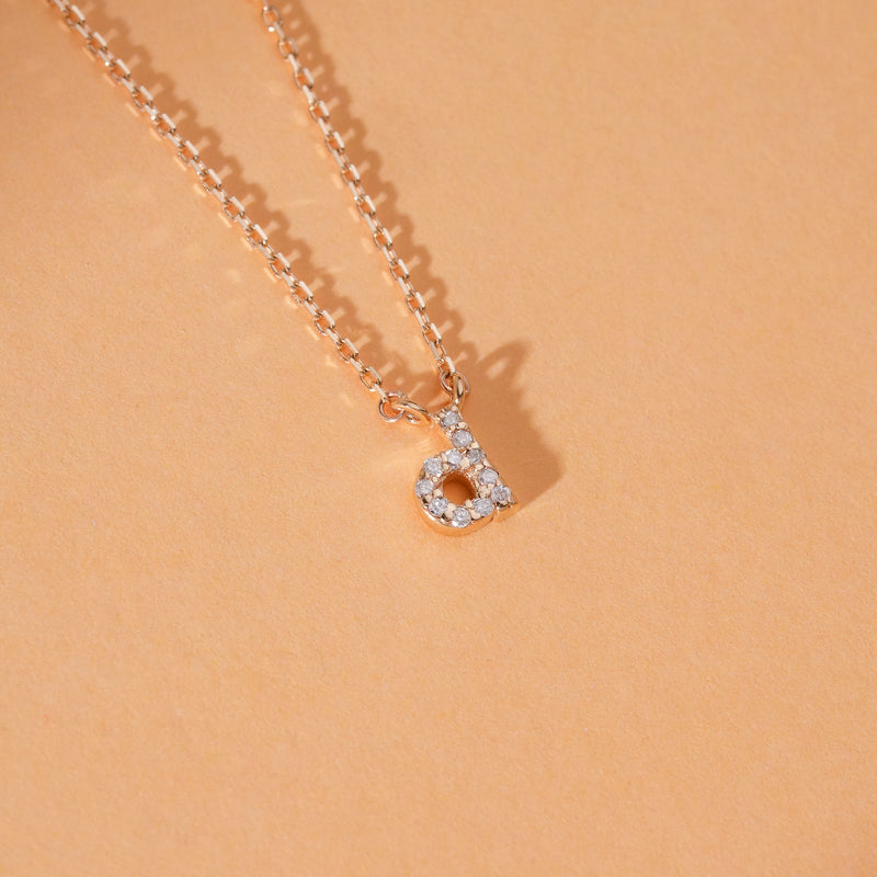 Close-up of diamond initial pendant featuring a sparkling diamond on a delicate gold chain.