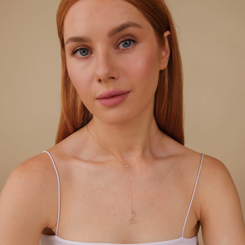 Delicate gold chain with a diamond snake pendant that curves and winds its way down the neckline.