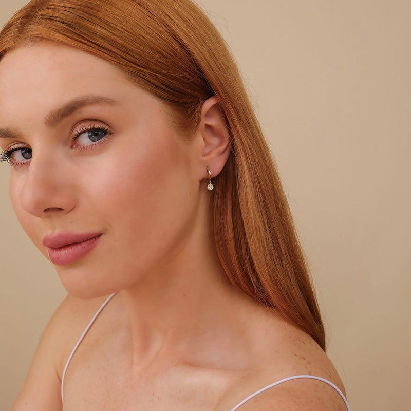 Model wears april birthstone clear diamond gifts for her with hanging paved diamond disc charm huggies