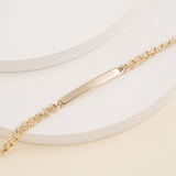 Solid gold nameplate bracelet on a chain.