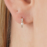 Dara Bring a touch of timeless luster and modern sparkle to your collection with our Pearl & Diamond Accent Huggie Hoops. Crafted in lustrous solid gold, these exquisite earrings feature a small hoop, partially lined with dazzling lab-grown diamonds. Anch