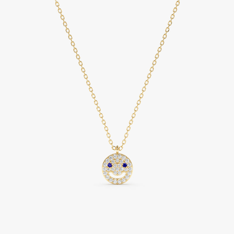Solid gold happy face pendant with diamond smile and blue sapphire eyes on a gold chain.