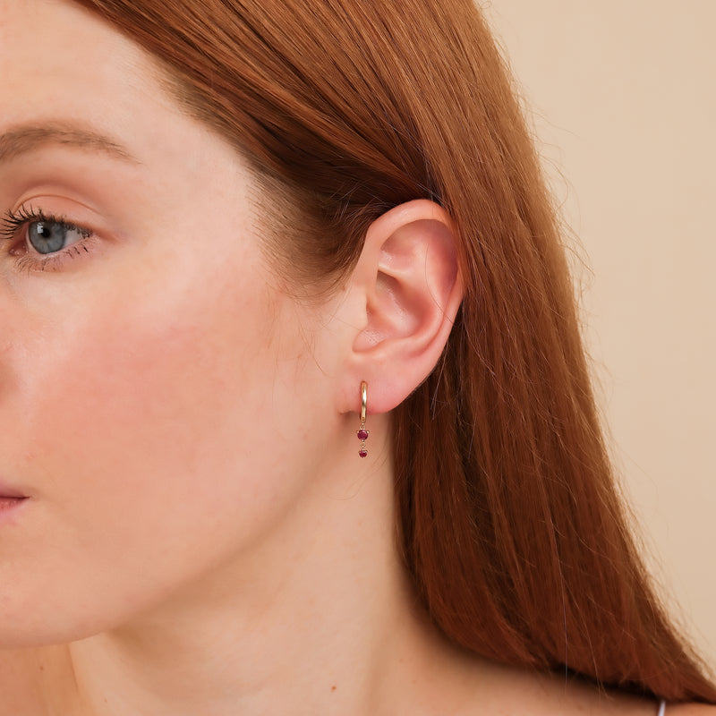 Model wears petite ruby gemstone gold hoop huggie