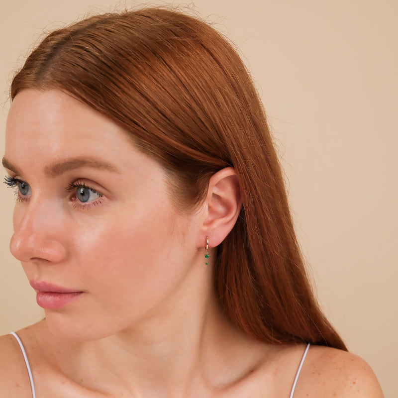 Model wears petite gold and emerald huggies 