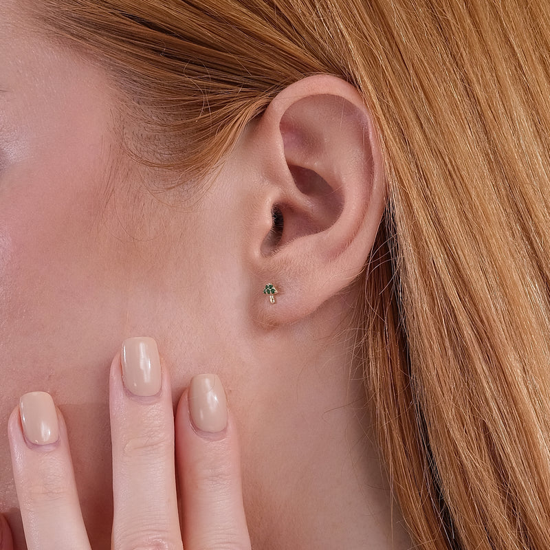 Model wears delicate mushroom shape stud earrings with emeralds in 14k solid gold. 