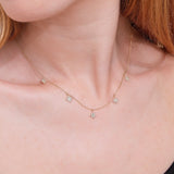 dainty solid gold necklace with five hanging diamond starburst drop charms