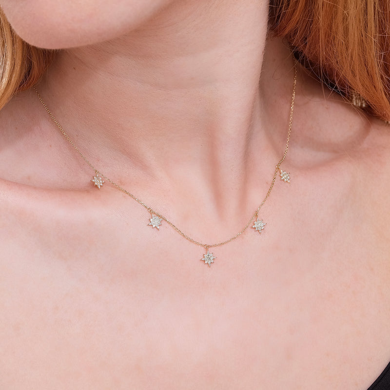 dainty solid gold necklace with five hanging diamond starburst drop charms