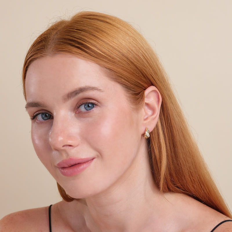 Model wears thick croissant style twist huggie with lined natural April birthstone diamonds gift for her. 