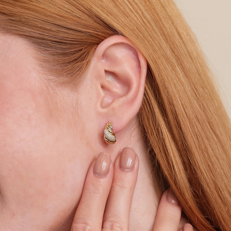 Model wears thick 14k solid gold croissant twist ear huggie in 14k solid gold with lined diamonds.
