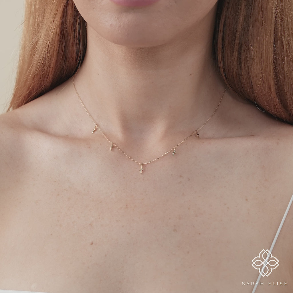 dainty chain necklace with five lightning bolt charms in gold.
