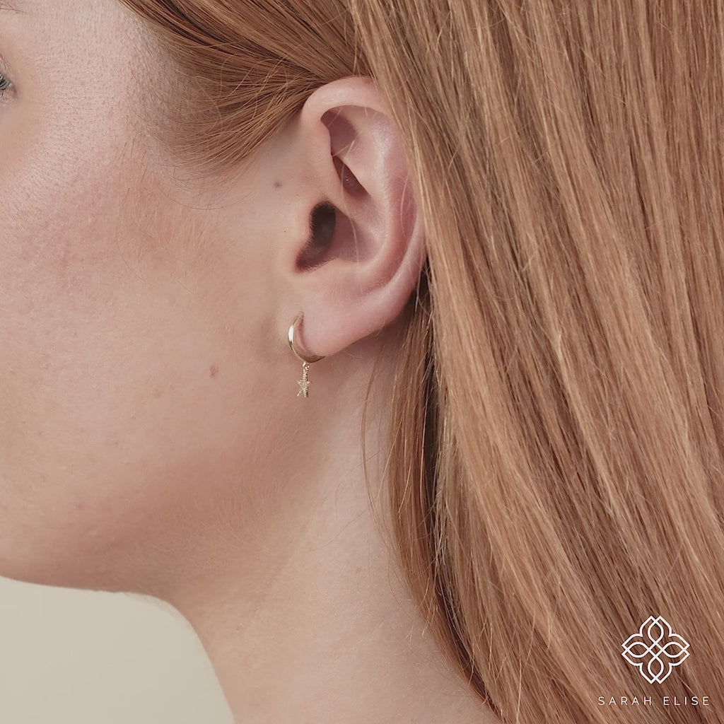 Video close up of ethically sourced star shaped huggie charm earring
