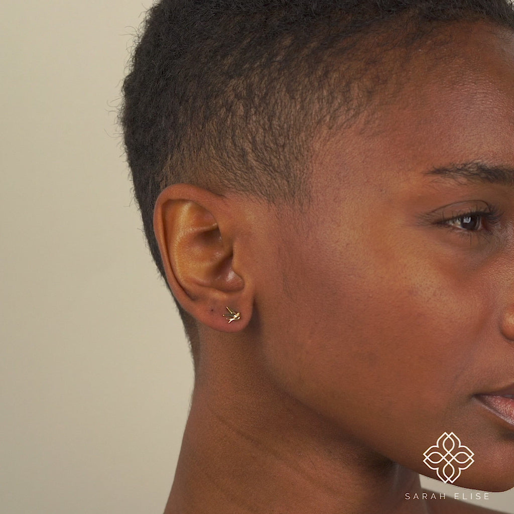 Video close up of model wearing dainty Solid Gold Small Bird Earring studs