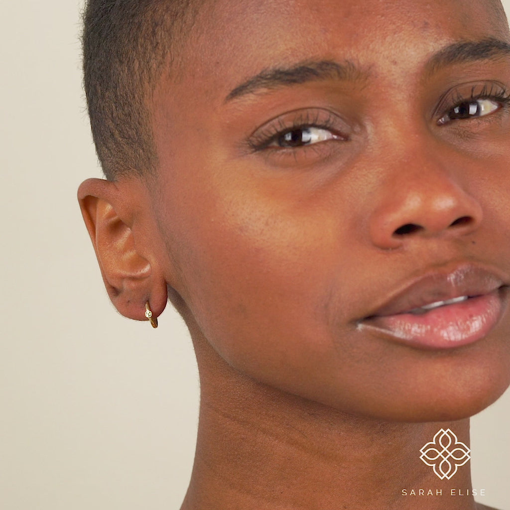 Video close up of model wearing solid 14k gold Peridot August Earrings