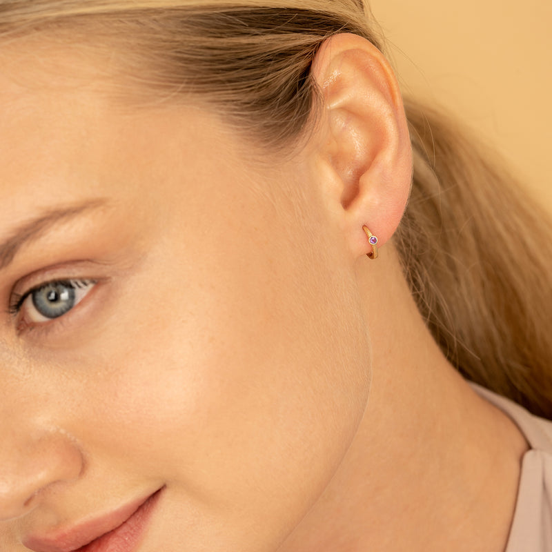 Model wears Tiny solid 14k Gold Amethyst Huggie Earrings