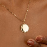 Diamond disc pendant on a gold paperclip chain.