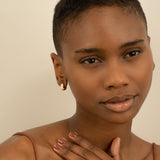 Model wears minimalist thick vintage inspired huggie earrings in 14k solid gold