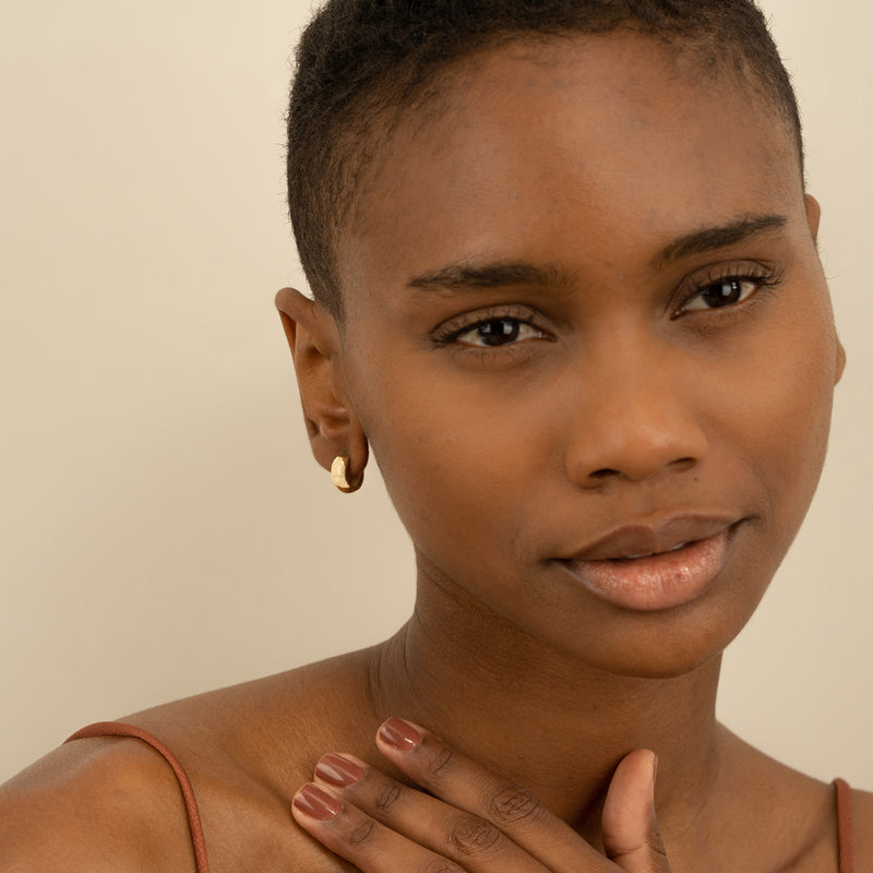 Model wears minimalist thick vintage inspired huggie earrings in 14k solid gold