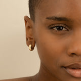 Model wears elegant handmade thick 14k solid gold huggies