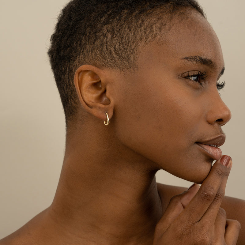 Model wears dainty solid gold U shape ear hoop huggie