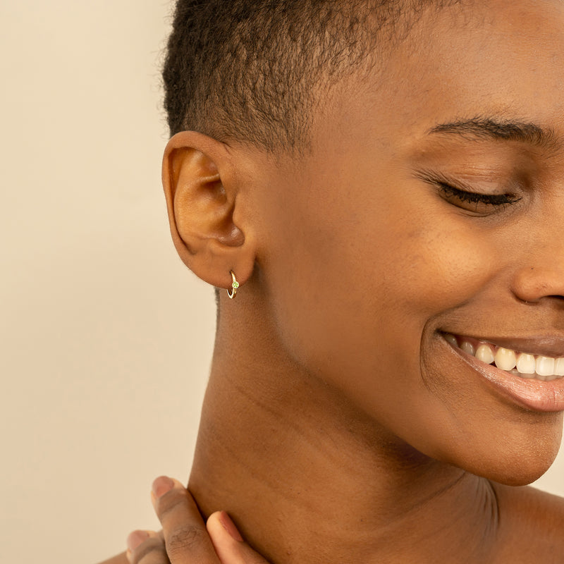 Model wears 14k solid gold Bezel Setting Peridot August Huggies