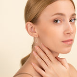 Model wears dainty 14k solid gold hanging chain link earring with diamonds