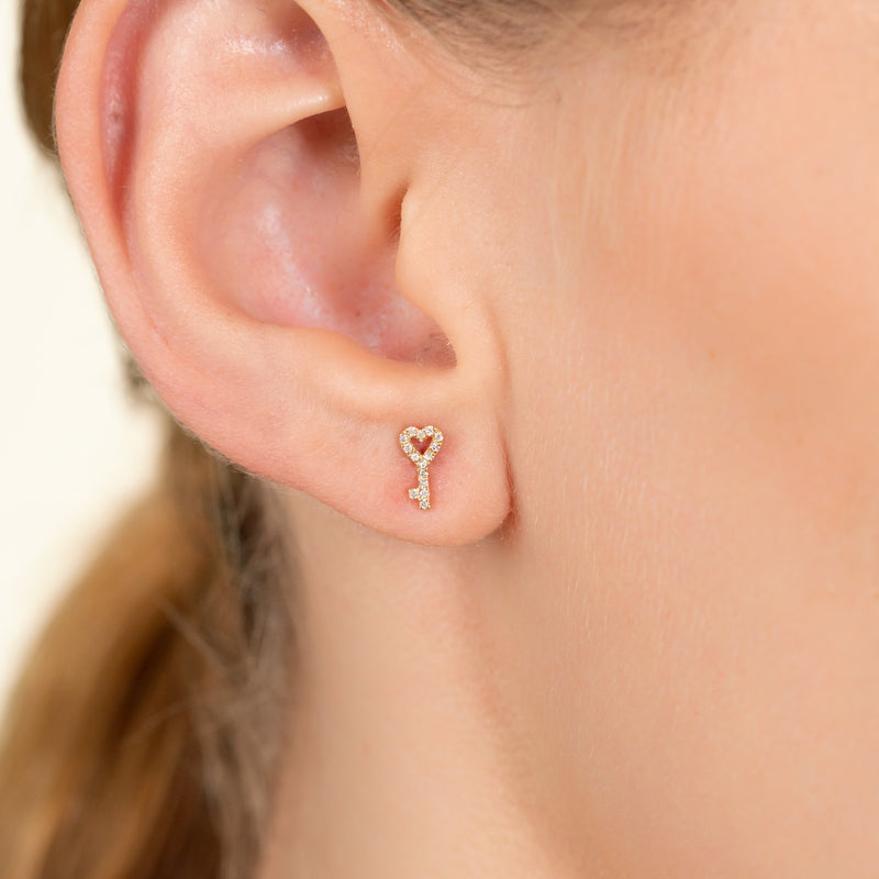 Model wears 14k solid gold diamond earring stud in key and heart shape