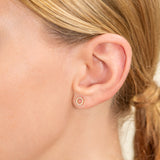 Model wears handmade dainty pair of 14k solid gold disc stud earrings lined in white natural dismonds