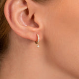 Model wears dainty solid 14k gold diamond lined hoop huggie earrings for her