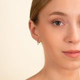 Dainty solid gold diamond lined hoop earring with dangling diamond bezel