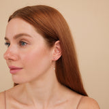 Model wears april birthstone long hanging diamond bezel earring stud
