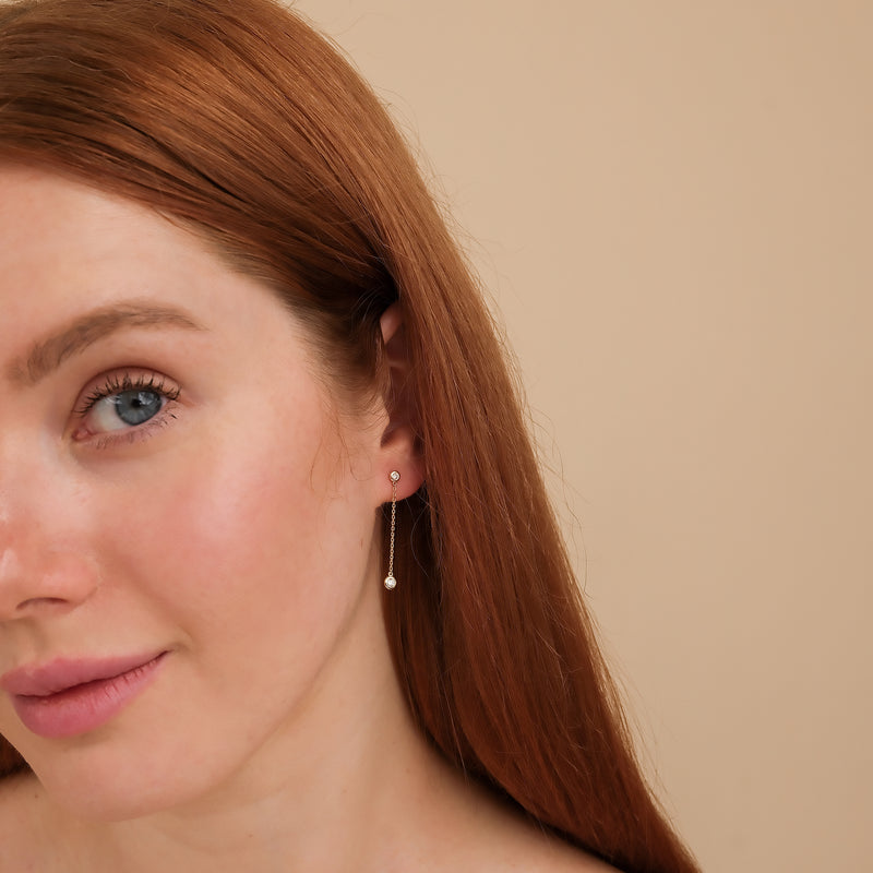 Model wears long hanging diamond bezel earring studs 