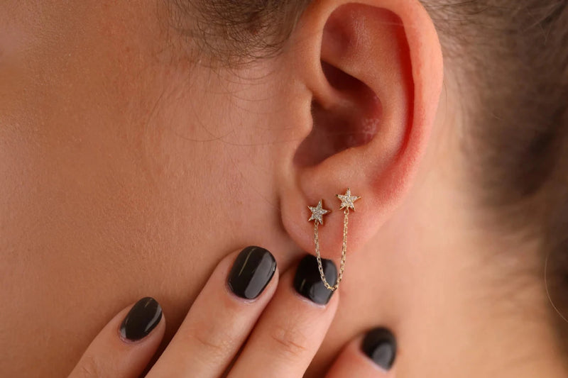 model wears dainty double star stud earrings with diamonds and hanging chain