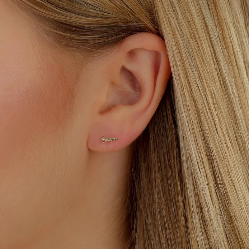 Model wears dainty pair of solid 14k gold screw stud earring